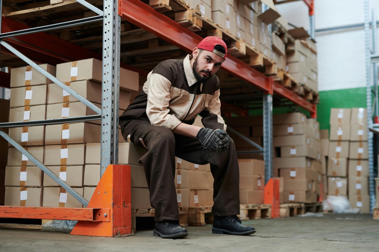 Warehouse worker sitting near stacked boxes